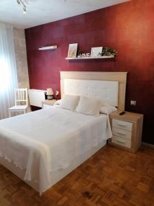 1 dormitorio con 1 cama blanca grande y pared roja en Apartamento Maracaibo, en Astorga