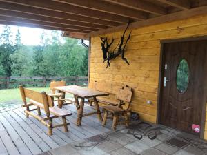 Ce chalet en bois comprend une table et des bancs en bois sur une terrasse couverte. dans l'établissement Domek Kozia Grapka, à Rajcza