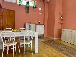 uma cozinha com paredes cor de laranja e uma mesa e cadeiras brancas em Nonna Maria Sweet Home em Castellana Grotte