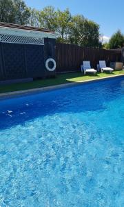 ein Schwimmbecken mit blauem Wasser und zwei Stühlen in der Unterkunft Richlands Homestay in Tondu