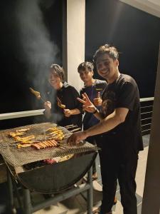 a group of people cooking food on a grill at RIVERSIDE PALM INN SG LEMBING in Sungai Lembing