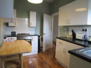 a kitchen with white cabinets and a wooden table at Woolly Hill House - Beautiful Townhouse in the Heart of Wooler in Wooler