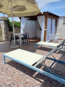 una mesa, sillas y una sombrilla en el patio en Casuzza Serena, en Granelli