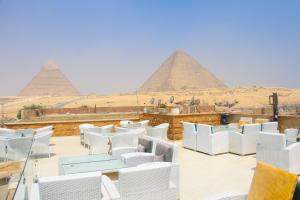 a view of the pyramids from a patio with white chairs and tables at Pyramids Valley Boutique Hotel in Cairo