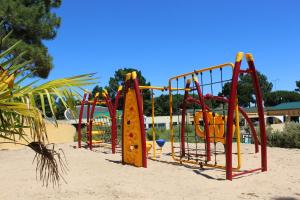 a playground with a bunch of play equipment in the sand at Le Domaine des Pins in Saint-Hilaire-de-Riez