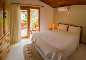 um quarto com uma cama branca e uma grande janela em Swiss Garten Jeri em Jericoacoara