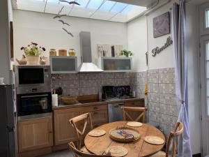 uma cozinha com uma mesa de madeira com cadeiras e uma cozinha com um frigorífico em La Terrasse de Compostelle T3 Chic, Charme, Cosy em Saint-Léonard-de-Noblat