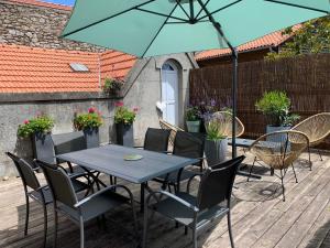 a table and chairs with an umbrella on a deck at La Terrasse de Compostelle T3 Chic, Charme, Cosy in Saint-Léonard-de-Noblat