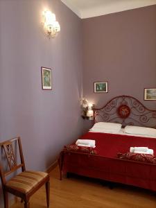 1 dormitorio con 1 cama roja y 1 silla en La Petite Maison, en Florencia