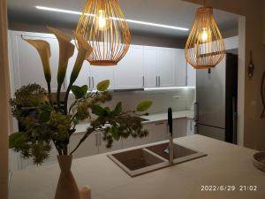 een keuken met witte kasten, een wastafel en verlichting bij Christina Kos Boutique Apartments in Kos-stad
