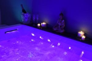 a woman sitting in a purple room with a tub with candles at Dedoor Luxury Appart in Molfetta +11 photos