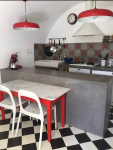 une cuisine avec une table rouge et deux chaises blanches dans l'établissement Casa Divota au cœur d’un village paisible, à Santa-Reparata-di-Balagna