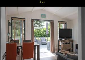 a living room with a table and a television at Inn To the beach in Ouddorp