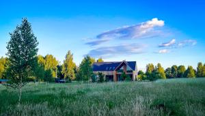 a house in the middle of a green field at TATANKA Dom Wakacyjny z sauną i balią z jacuzzi in Białowieża
