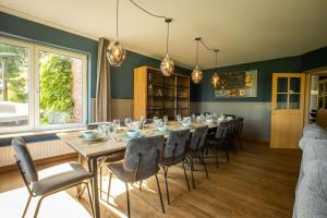 een eetkamer met een lange tafel en stoelen bij Blauwe Hoeve Luxe, ruimte, privacy en rust in Retranchement