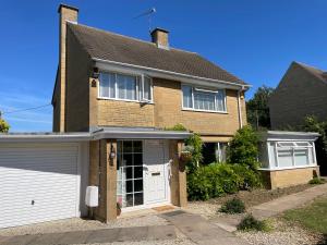 a brown brick house with a white garage at Penderels, Willersey in Broadway