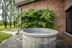 uma grande banheira de madeira ao lado de um edifício de tijolos em Blauwe Hoeve Luxe, ruimte, privacy en rust em Retranchement