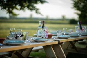 una mesa de madera con copas, platos y botellas de vino en Blauwe Hoeve Luxe, ruimte, privacy en rust, en Retranchement