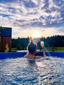 a woman in a swimming pool holding a glass of wine at TATANKA Dom Wakacyjny z sauną i balią z jacuzzi in Białowieża