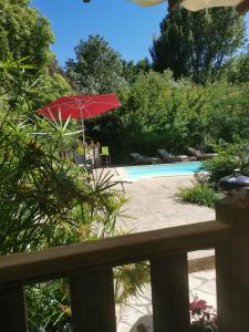 Saint-PrivatLe P'tit gîte的游泳池旁的一把红色遮阳伞