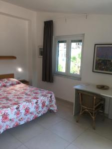 een slaapkamer met een bed, een bureau en een raam bij Residence Santa Maria Suites in Marina di Camerota