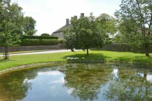 a pond in a yard with a house in the background at Sandy's Barn, Foolow, Dogs Welcome in Foolow