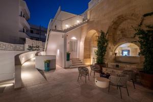 un patio con sillas y mesas y un edificio en Dimora San Giuseppe Hotel & SPA, en Otranto
