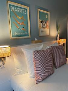 uma cama com almofadas brancas num quarto em Hotel De L'Océan em Biarritz