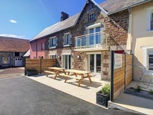 a wooden picnic table in front of a brick building at petite maison proche centre ville in Bréhal