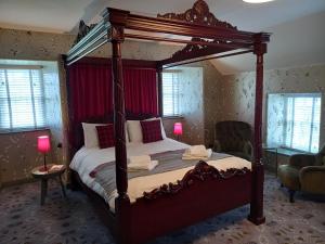 a bedroom with a large canopy bed with red curtains at Monkstadt 1745 Restaurant with Rooms in Portree