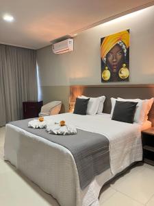 a bedroom with a large bed with a painting on the wall at Pousada Casa Kuavá Experience in Maragogi