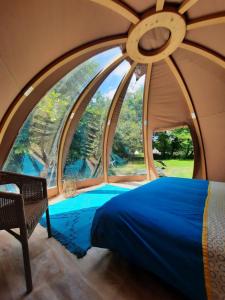 a bed in a room with a large window at Wigwam 1 Domaine du Pas de l'âne in Mios