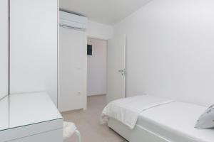 a white bedroom with two beds and a mirror at Villa Pinia Fazana in Fažana