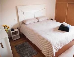 een slaapkamer met een groot bed met een witte sprei bij Ático Guara&Pirineos in Huesca