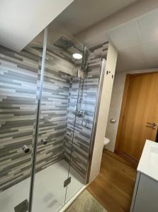 a shower with a glass door in a bathroom at Ático Guara&Pirineos in Huesca
