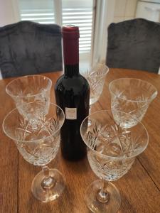 a bottle of wine and three wine glasses on a table at Vila Bartulović in Kučiće