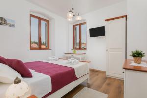 a white bedroom with a bed and a tv at Ancora Faros in Stari Grad