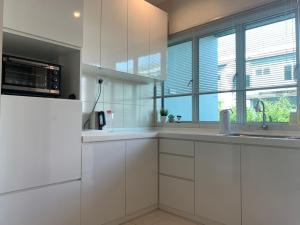 una cucina con armadi bianchi, lavandino e finestre di Omari Marina Island Homestay Lumut a Lumut