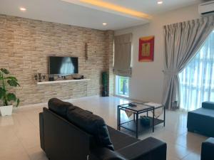 a living room with a couch and a tv on a brick wall at Marina Island Tiara Bay Villa in Lumut