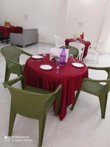 une table avec une nappe rouge et des chaises vertes dans l'établissement Bundeli Farm Resort & Banquet Orchha, à Orchha