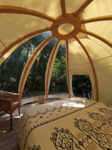 a bed in a tent with a large window at La Wigwam Blanche du Domaine du Pas de l'âne in Mios