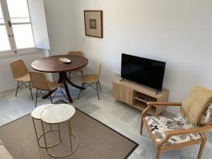 a living room with a tv and a table and chairs at el 2 de Flamenco Ático 3ºB in Cádiz
