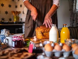 un hombre está cortando una barra de pan con un cuchillo en Cosy Cottage with Spa, Catering, Nature Reserve Walks, Large Garden, Free Parking - Self Checkin, en Scunthorpe
