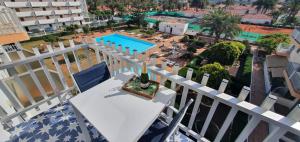 a white balcony with a table and a view of a pool at Sunset Apartment in Playa del Ingles