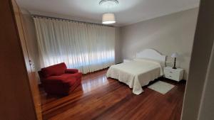 a bedroom with a bed and a red chair at Casa del Patio in Cangas de Morrazo