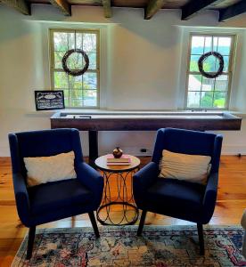 two chairs and a table in a living room with windows at Downingtown Manor - 1900s Farmhouse with Creek Views in Downingtown