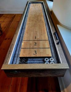 a wooden table with a clock on top of a floor at Downingtown Manor - 1900s Farmhouse with Creek Views in Downingtown