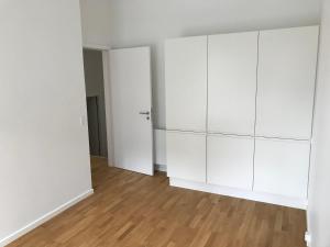 an empty living room with white cabinets and wood floors at Big Room In SHARED APARTMENT With King Size Bed in Copenhagen