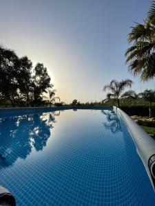 een blauw zwembad met bomen op de achtergrond bij Villa Oleandra Relais in Partinico