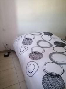 Una cama con una manta blanca con círculos negros y grises en EVANA, en Bize-Minervois